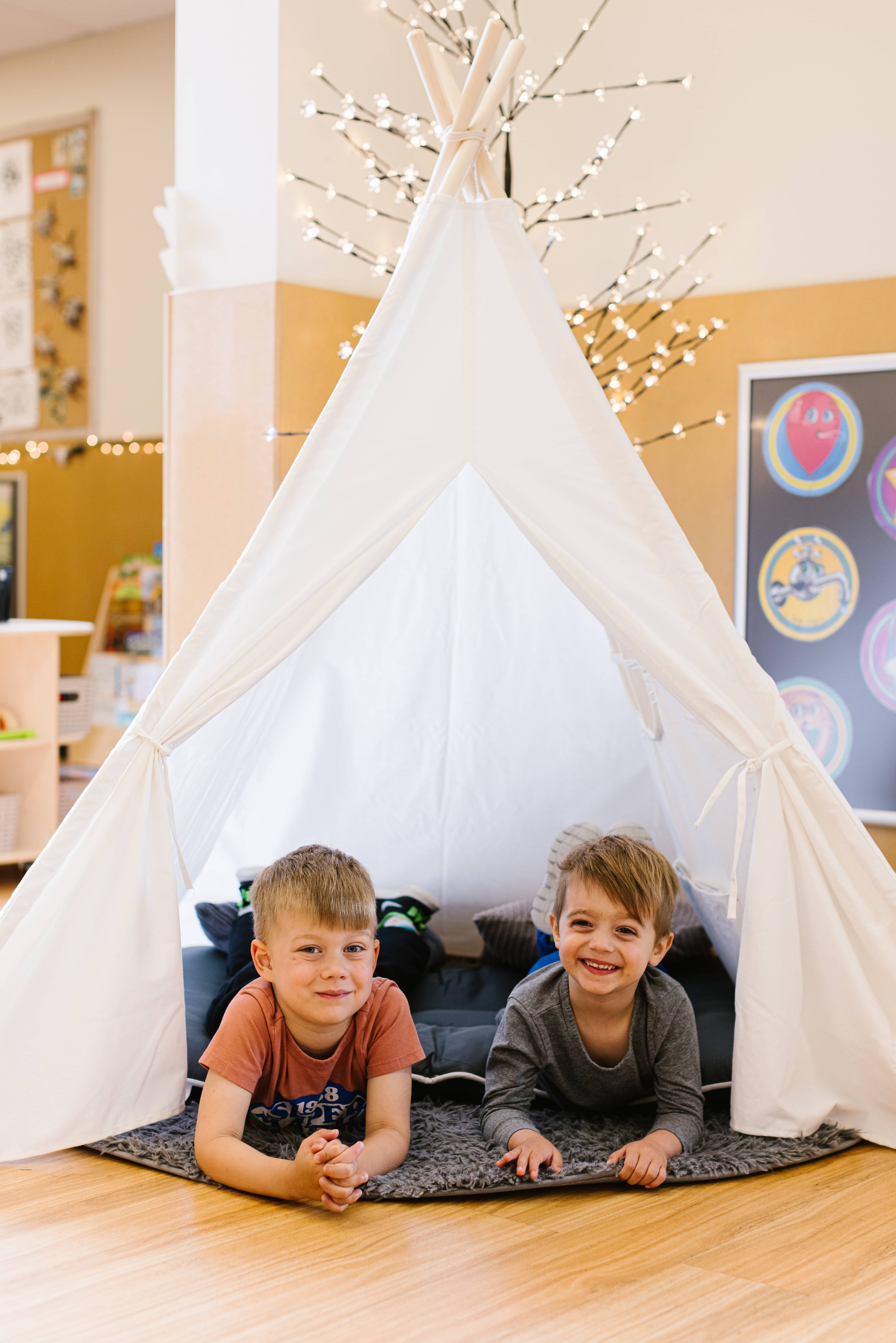 Two children smiling inside a play tent at Marlborough Day Nursery